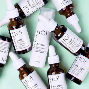 A group product photo of several 101 serums scattered on a light mint background.