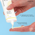 Hand holding an opened tube of Zero Feel cream with a blue background, the product is coming out of the tube. The texture of the product is creamy. The text on the image says: _how to use:

1. apply generously to the face as the last step of your AM routine

2. can be used around the eyes - it won’t sting 
